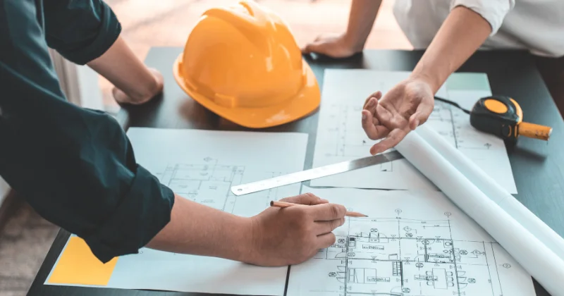 Two engineers reviewing technical plant drawings and planning a chemical process