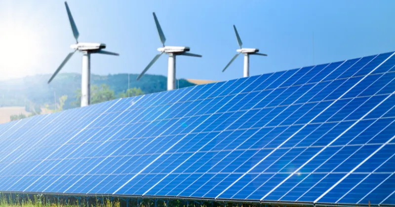Solar panels and wind turbines converting renewable energy into electricity, illustrating the First Law of Thermodynamics.
