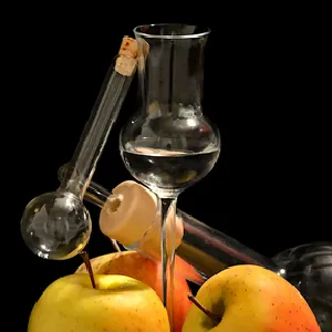 Glass of fruit-based distilled alcohol with apples and a traditional glass pipette