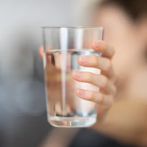 Hand holding a clear glass of drinking water