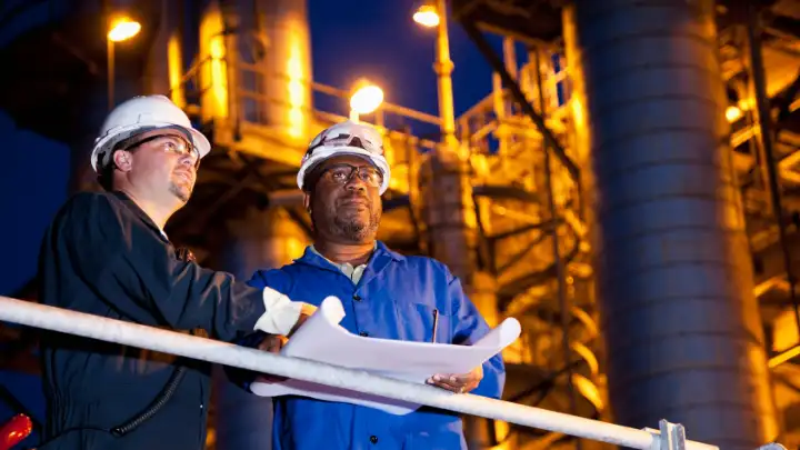 Chemical engineer reviewing process drawings in an industrial plant environment